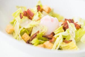 A salad with bacon and lettuce in a white bowl photo
