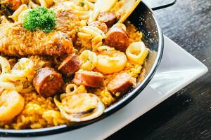 A pan with rice, meat and seafood on top photo