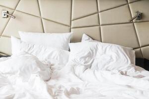An unmade bed with white sheets and pillows photo