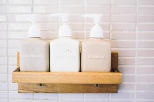 Three bottles of soap are on a wooden shelf photo