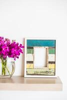 A wooden shelf with a vase of purple flowers photo