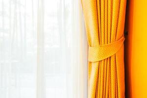 A yellow curtain is hanging in front of a window photo