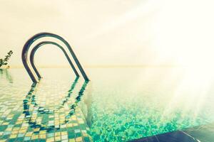 A pool with a ladder and sun shining through it photo