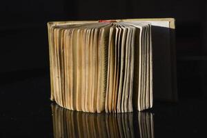 Old book. Opened old book with yellow stained pages on the black background. Education concept. photo