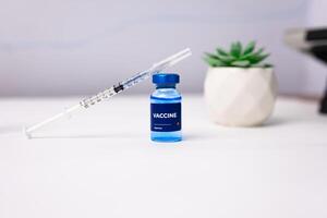 blue vaccine with syringe on top of it on a white table. health and medical concept photo