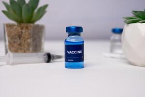 a blue vaccine with syringes, vials and ornamental plants behind it. medical concept photo