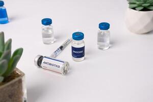 several vials and a syringe on a white table. health and medical concepts photo