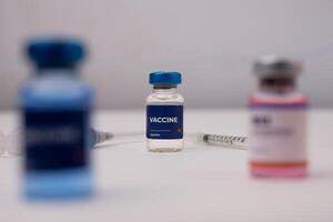 a vaccine and a syringe with a blurred vial in front of it. medical concept photo