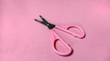 Small pink scissors on a pink background. Concept of cutting, crafting, and precision. photo