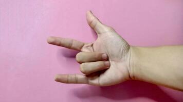 Close up of a hand forming the 'I love you' sign language against a pink background. Concept of love, affection, and communication. photo