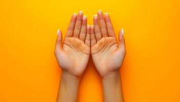 Two hands are shown with a yellow background. The hands are open and facing each other. Concept of connection and warmth between the two hands photo