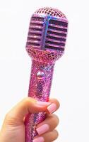 A pink microphone with glittery decorations. The microphone is held by a person's hand. Concept of fun and creativity, as the microphone is decorated with glitter and he is a toy or a novelty item photo