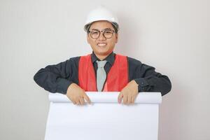 portrait of handsome asian architect wearing white helmet rolling up blueprint document, architectural concept designing and designs for construction. photo