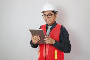 Confident asian engineer man Using tablet for checking and maintenance to inspection at modern home building construction. Architect working with white safety helmet in construction site photo