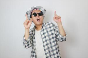 Asian man traveler hold luggage gentle smile gesture point finger white background. photo