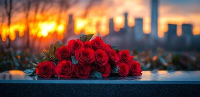 Red roses placed on a grave at sunset in the city. A bouquet of red roses sits on a gravestone, with the sun setting behind the city skyline. photo