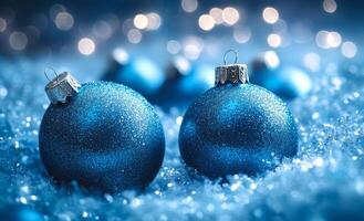 Two blue ornaments with silver hooks on them are sitting on top of a snowy surface. The scene is festive and cheerful, with the blue ornaments adding a pop of color to the winter landscape photo