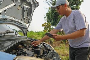 Auto check up and car service shop concept. Mechanic writing job checklist to clipboard to estimate repair quotation to client at workshop garage. photo