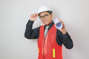 Young handsome chinese architect man wearing glasses and safety helmet holding blueprints surprised with an idea or question pointing finger with happy face, number one photo