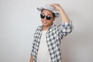 emocionado joven viajero turista asiático hombre en casual ropa sombrero sostiene ciudad mapa durante el excursión, mirando aparte en amarillo antecedentes. pasajero de viaje en fin de semana. aire vuelo viaje concepto foto