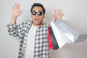 Funny surprised and shocked face of Asian man see product in the shopping bag photo