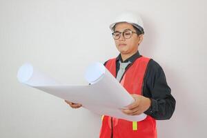Young handsome asian man in casual dress with white hardhat hand holding paperwork blueprint in architect and engineer worker isolated in white background in studio photo