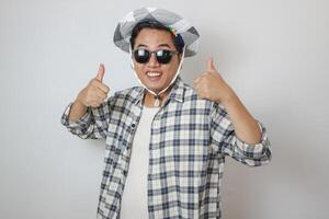 Overjoyed asian man wearing sunglasses dancing, makes movements to music, smiles positively, being in high spirit. isolated on blue background. holiday and vacation concept. photo