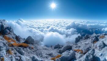 A mountain range with a clear blue sky and clouds. The clouds are white and fluffy, and the sun is shining brightly. The scene is peaceful and serene, with the mountains photo