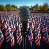 A microphone is pointed at a large crowd of American flags. The microphone is black and silver. The flags are red, white, and blue photo