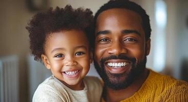 A man and a child are smiling at the camera. The man is wearing a yellow sweater and the child is wearing a white shirt. Scene is happy and warm photo