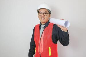 Young Asian civil engineer or construction supervisor wearing a helmet looks away and smiles while inspecting a construction site. photo