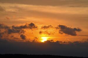 A red sunset on a background of clouds. The setting sun over the forest in summer. photo