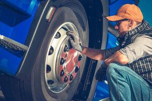 Mechanic Inspecting Semi Truck Tire in Bright Workshop During Afternoon photo