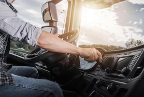 Driver Adjusting Controls While Operating a Large Truck During Sunset on the Highway photo