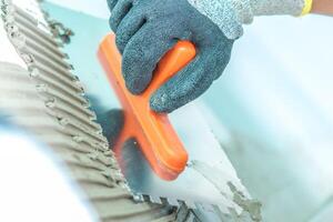Worker Using a Trowel to Apply Mortar on a Construction Site in Bright Daylight photo