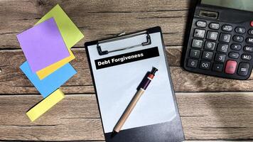 Concept of Debt Forgiveness write on paperwork isolated on Wooden Table. photo