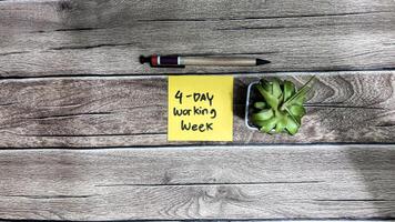 Concept of 4 day working week write on sticky notes isolated on Wooden Table. photo