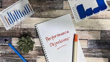 Concept of Performance Objectives write on book isolated on Wooden Table. photo