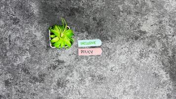 Concept of Inclusive Policy write on sticky notes isolated on Wooden Table. photo