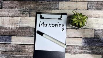 Concept of Mentoring write on paperwork isolated on Wooden Table. photo