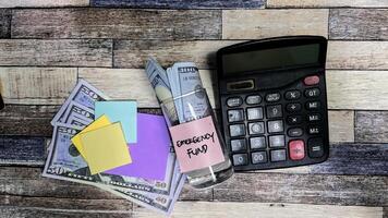 Concept of Emergency Fund write on sticky notes on a glass isolated on Wooden Table. photo