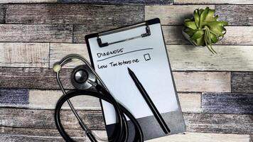 Concept of Diagnosis Low testoterone write on paperwork isolated on Wooden Table. photo