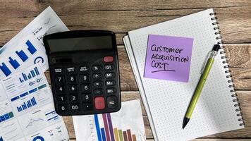 Concept of Customer Acquisition Cost write on sticky notes isolated on Wooden Table. photo