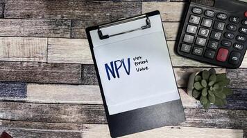 Concept of NPV - Net Present Value write on sticky notes isolated on Wooden Table. photo
