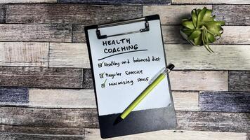 Concept of Health Coaching write on paperwork, Supported by an additional services isolated on Wooden Table. photo