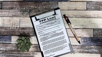 Concept of PPP Loan Forgiveness write on form isolated on Wooden Table. photo