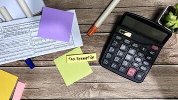 Concept of Tax Exemption write on sticky notes isolated on Wooden Table. photo