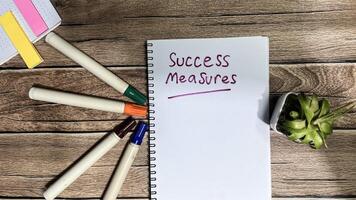 Concept of Success Measures write on book isolated on Wooden Table. photo