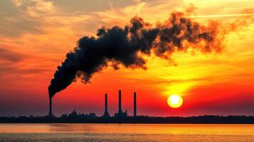 A factory with smoke coming out of it at sunset photo