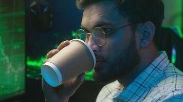 Arabian Indian man holding cup drinking coffee male programmer coder technology cryptocurrency bitcoin work trader network freelance guy businessman e-commerce hacker crypto developer business home video